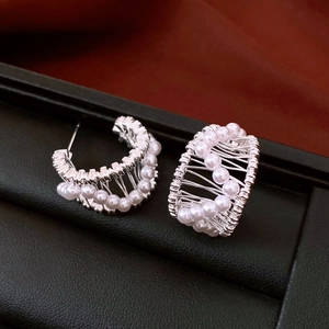 Macro view of C-shaped hollow earrings with 18k gold plating and small white pearls