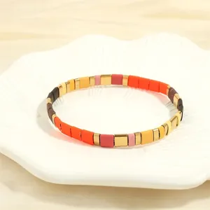 Detail of bohemian Tila bead bracelet with matte orange and pink beads on a shell plate