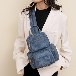 Vintage washed blue PU backpack shown on model with multiple functional zipper pockets