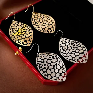 Hollow leaf tassel drop earrings in gold and silver finish displayed in a jewelry box