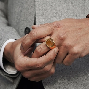 Detailed view of a vintage gold signet ring with brown gemstone on a male model hand