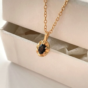 Elegant 925 sterling silver gold necklace with oval black gemstone pendant on a jewelry box