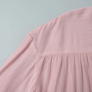 Macro detail of pink pleated fabric showing fine ruffled texture and lantern sleeve stitching