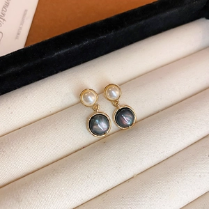 Detailed close-up of retro gold-plated oval stud earrings with pearl and black shell inlay