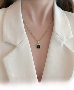 Detail of emerald green rectangular pendant necklace on gold chain with minimalist setting