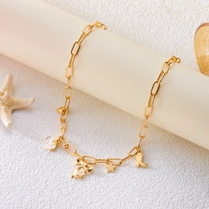 Detail of gold chain necklace featuring shell, bow, and star charms on a display