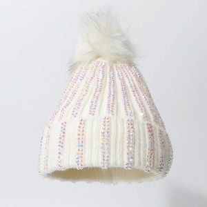 Close-up of white knit beanie with sparkling rhinestones and a fluffy faux fur pompom