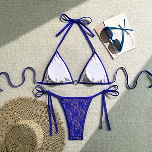 Detailed flat lay of royal blue lace bikini with gold ring detail on textured mat