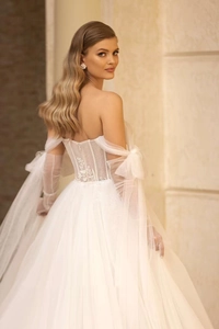 Dettaglio dell'abito da sposa bianco con ricami floreali e guanti in tulle velato
