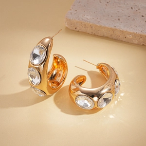 Detail of golden multilayer hoop earrings with three large clear crystals on stone base