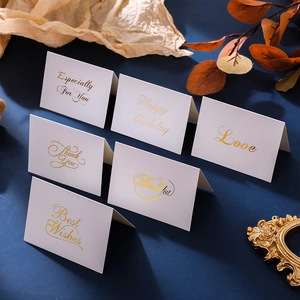 Detailed view of six white cards with gold foil lettering and various greetings on blue background