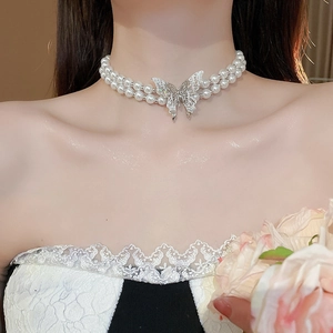 Close-up of double-layer pearl necklace with silver butterfly pendant on woman neck