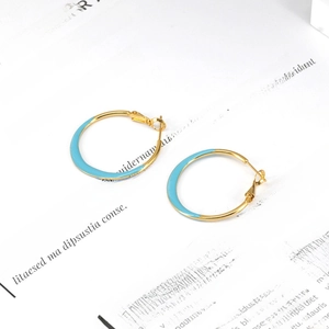 Macro view of blue enamel and gold finish geometric hoop earrings on a text background
