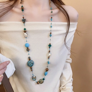 Close-up of bohemian layered beaded necklace with turquoise and floral accents on a model
