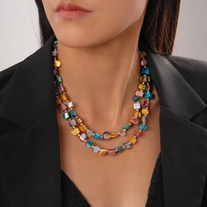 Close-up of a double-layered beaded necklace with colorful irregular shells on a model