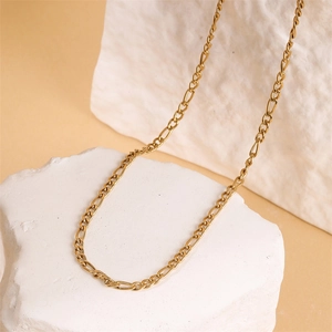 Golden Figaro chain necklace made of stainless steel displayed on white textured stones