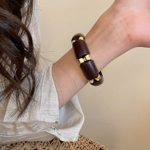 Detail view of retro acrylic beaded bracelet in brown and gold on a model's wrist
