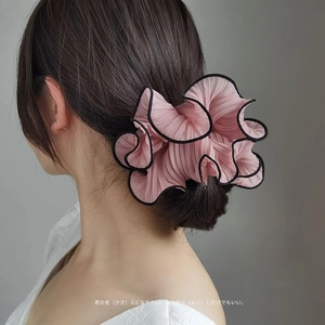 Pink pleated scrunchie with black trim, oversized hair tie worn by a model in a high view