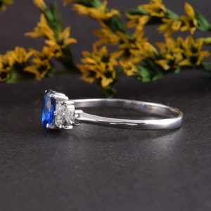 Macro zij-aanzicht van een zilveren ring met blauwe saffier en diamant accenten