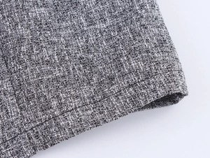 Close-up of the grey tweed fabric texture and precise stitching on the hemline