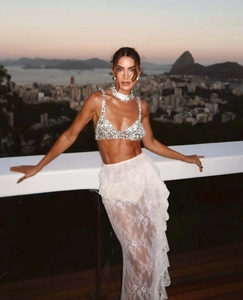 Dettaglio del crop top con paillettes argento e gonna lunga in pizzo bianco con volant