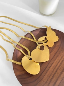 Three gold snake chain necklaces with butterfly, heart and oval pendants on wooden tray