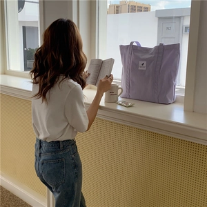 Minimalist purple canvas tote bag shown in a cozy lifestyle setting with female model