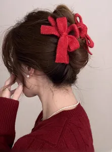 Detail view of a large red knitted bow hair claw clip styled on a woman's hair
