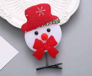 Detalle de un clip para el pelo de muñeco de nieve navideño con gorro rojo y muelle