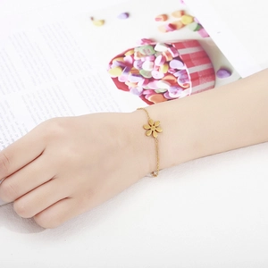 Detail shot of a minimalist gold flower bracelet with adjustable chain on a model wrist