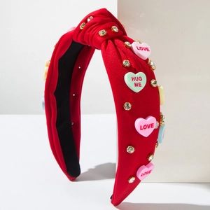 Close-up of red fabric headband featuring LOVE and HUG ME heart charms with rhinestones