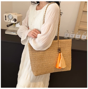 Detailed shot of straw tote bag featuring colorful tassels and wooden beads decor