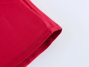 Gros plan détaillé montrant la texture du tissu rouge et la double couture de la robe