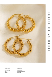 Détail de boucles d'oreilles dorées à perles et torsadées sur tissu en soie beige