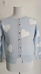 Detail of light blue knit cardigan with white heart patterns and marble buttons