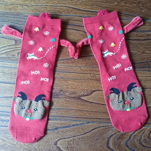 Detail of red Christmas socks with 3D magnetic hands and snowflake deer patterns