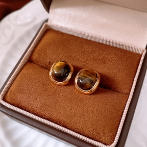 Detail of 18k gold plated tiger eye stone stud earrings in a luxury jewelry box