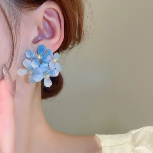 Close-up of blue gradient flower earrings with silver needles and crystal details