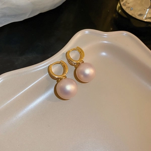 Close-up of gold geometric hoop earrings with polished pinkish pearl drops on a tray