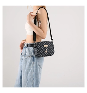 Detail of black monogram crossbody bag with gold deer charm and adjustable leather strap