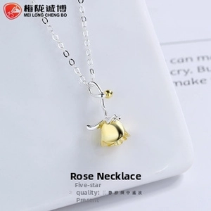 Dettaglio di una collana a rosa in argento con testa di fiore dorata su supporto bianco