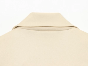 Détail du col à revers en tissu sergé beige et coutures précises sur le gilet court