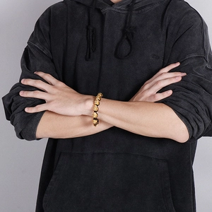 Detailed shot of men's skull bead bracelet featuring golden metal skulls on black cord
