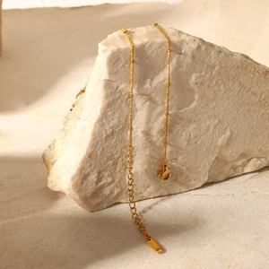 Dettaglio della collana a catena dorata con sfere e chiusura a moschettone su pietra