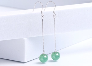 Detail of silver drop earrings with green aventurine beads on white geometric display