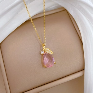 Vue détaillée du pendentif larme rose avec feuilles dorées sur fond de soie douce