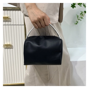 Detail of a black matte leather handbag with a sleek silver metal arched handle