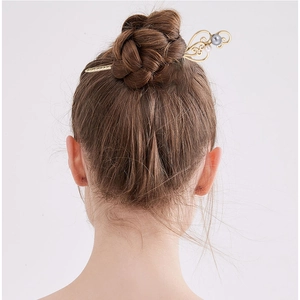 Detailed back view of golden metal hairpin with pearls styled in an elegant updo