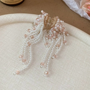 Detail of the pearlescent tassels and amber shark hair claw with pink beads