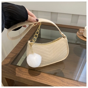 Vue détaillée d'un sac à main beige matelassé en V avec chaîne dorée et pompon en peluche